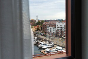 Marina com barcos atracados, roda gigante ao fundo e edifícios com telhados vermelhos.