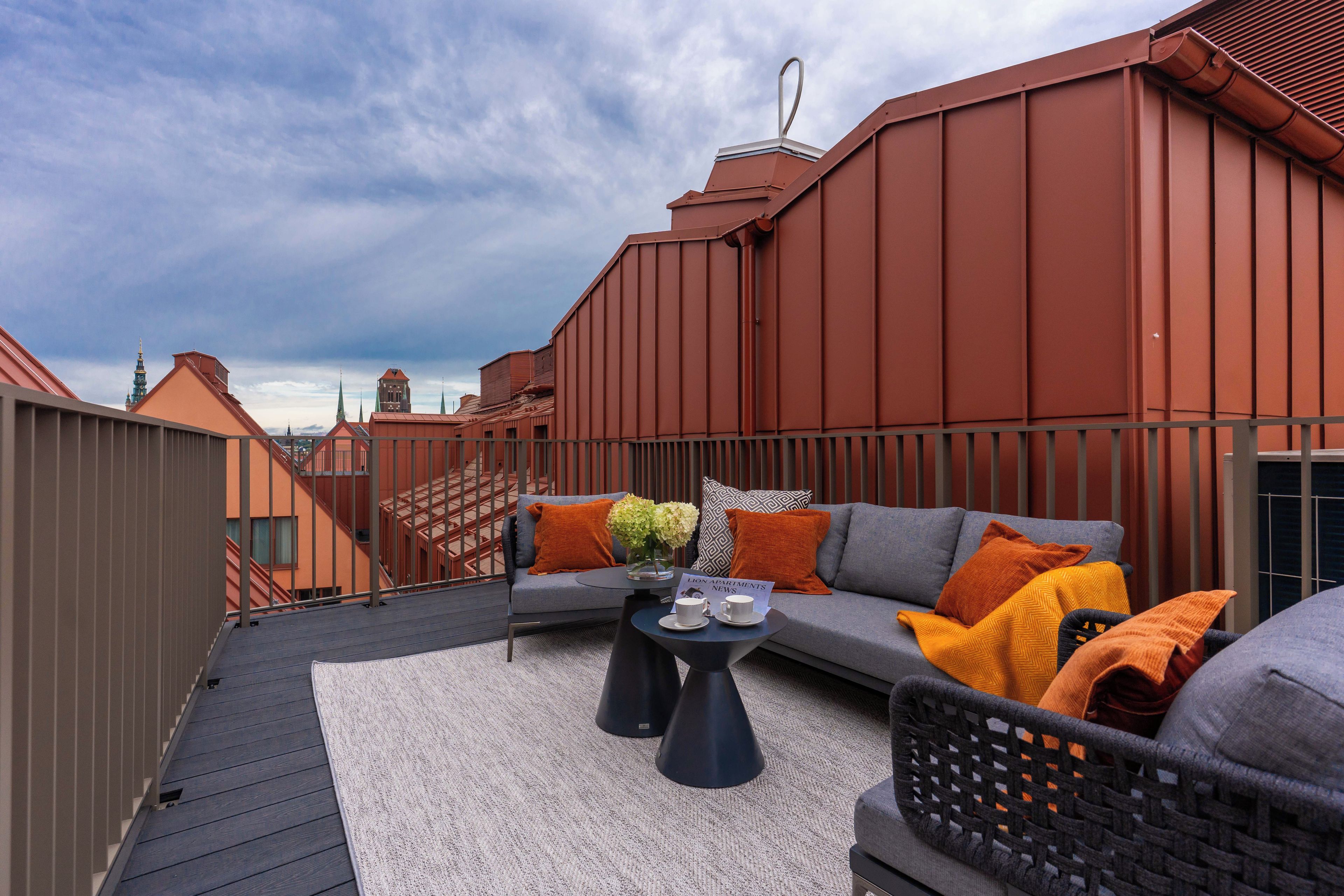 A rooftop terrace with a sofa, coffee table, and a view of the city skyline.