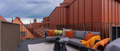 A rooftop terrace with a sofa, coffee table, and a view of the city skyline.