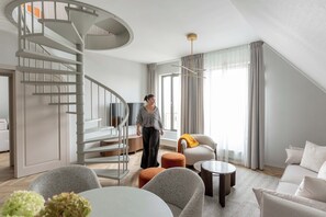 Ein modernes Wohnzimmer mit einer Wendeltreppe, einer Sofagarnitur, einem Couchtisch und einem Esstisch.