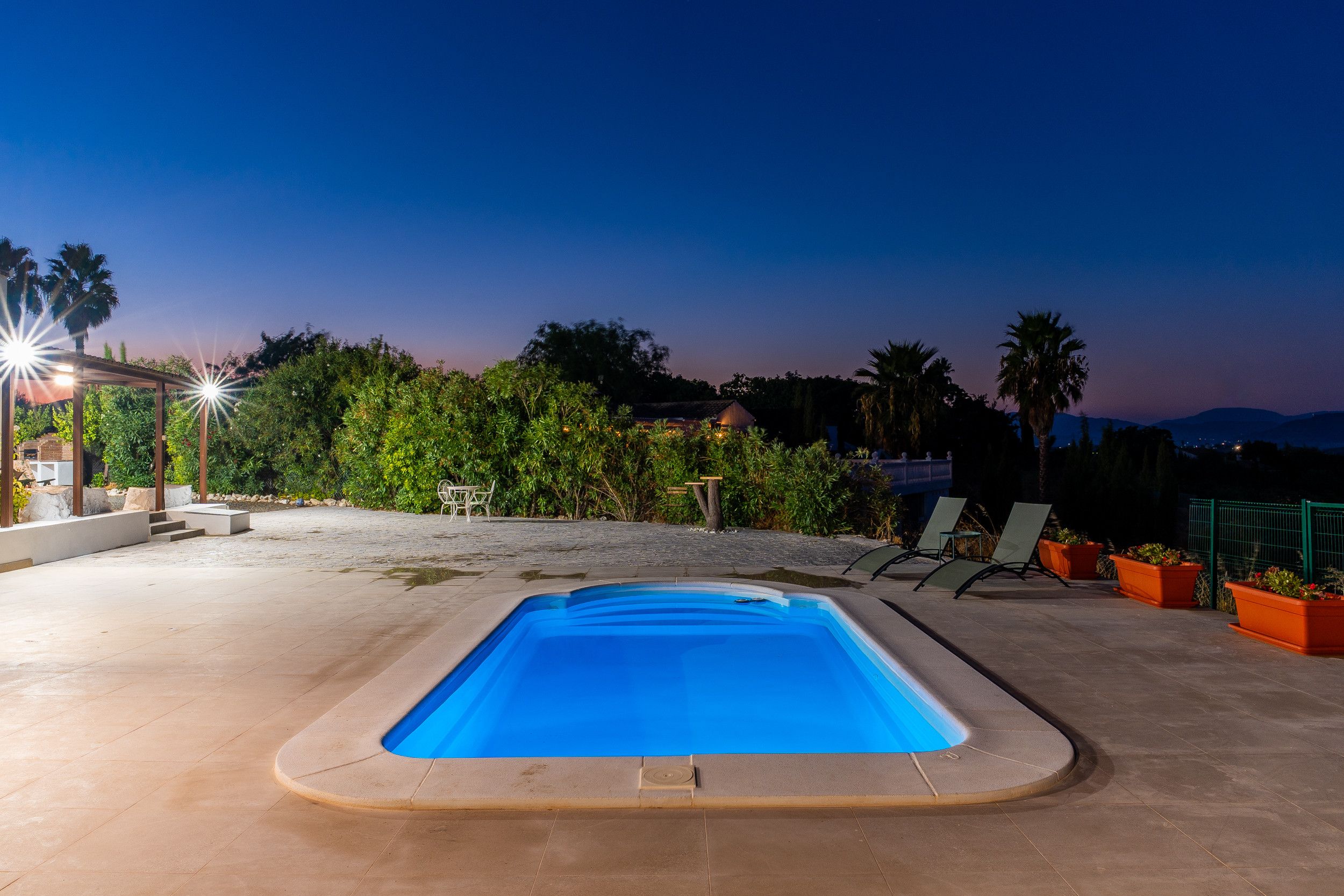 Ein Swimmingpool mit glasklarer, blauer Wasseroberfläche, umgeben von einer gepflasterten Liegefläche.