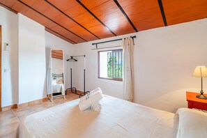 A bedroom with a bed, a window with curtains, a bedside table with a lamp, a hanging light fixture, and a mirror. - Cubo's Casa El Farol / Private pool / BBQ / Free Wi-Fi (Alhaurín el Grande)
