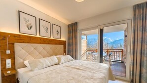 Una camera da letto con un letto grande, una testiera in legno e un balcone con posti a sedere esterni.