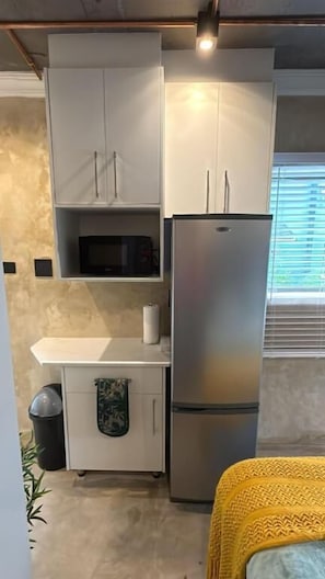 A compact kitchen with a microwave, refrigerator, and a small countertop. - Falcons Rest  (Pretoria)