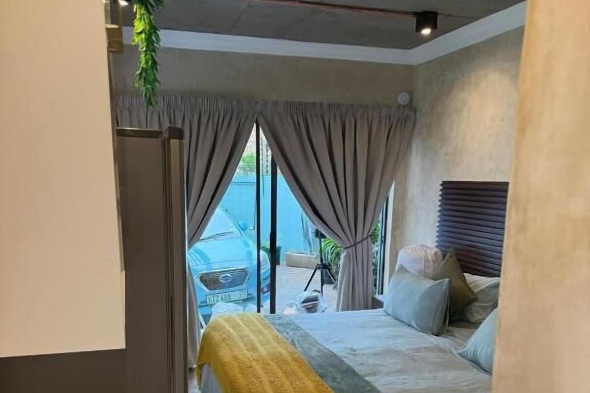 A bedroom with a bed, curtains, and a view of the outside.