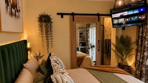 A hotel room with a bed, a TV mounted on the wall, a sliding door, and a plant. - Falcons Rest  (Pretoria)