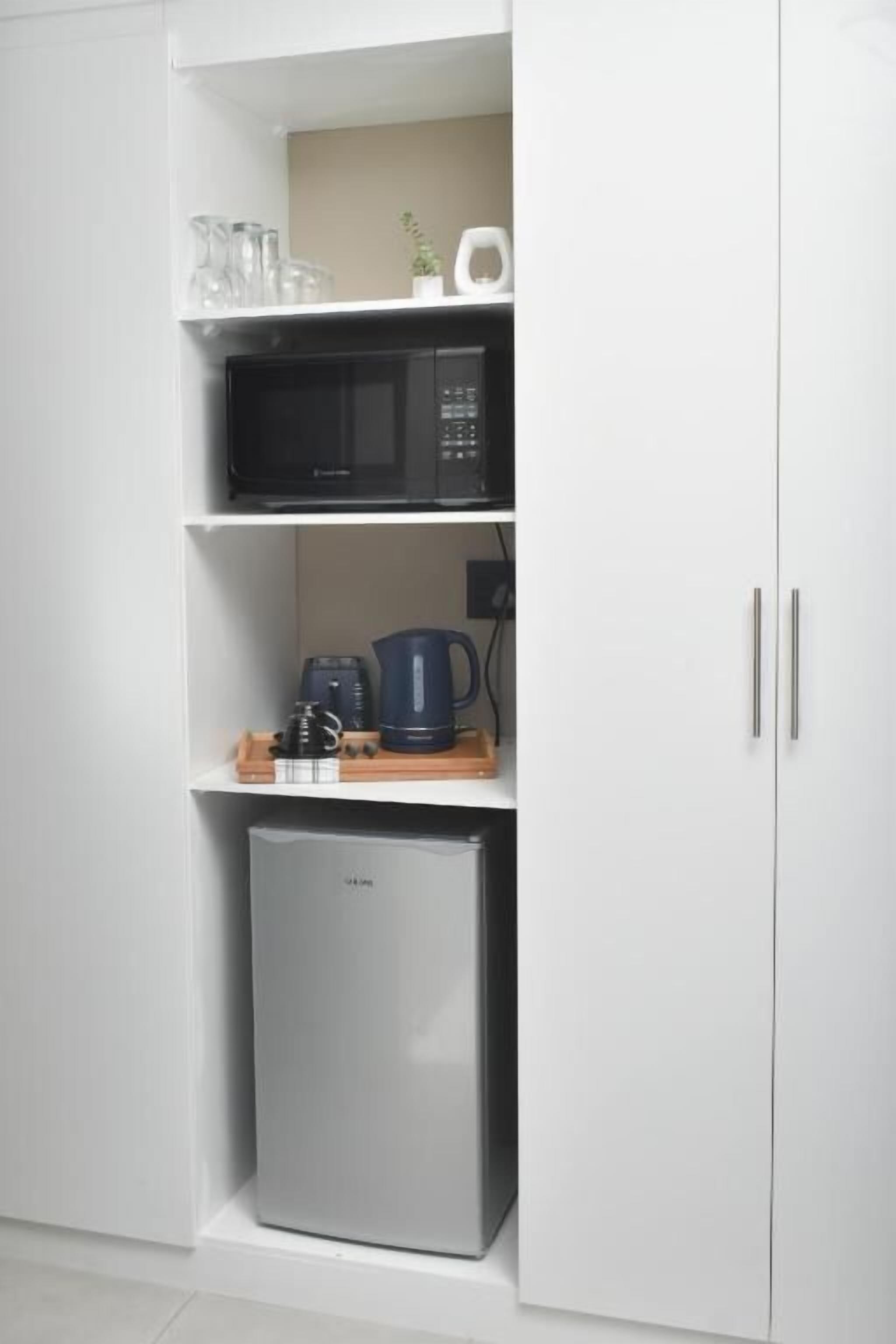 A kitchen with a microwave, coffee maker, and a refrigerator.