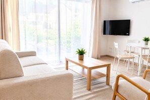 Ein modernes Wohnzimmer mit einer Couch, einem Couchtisch und einem an der Wand befestigten Fernseher.