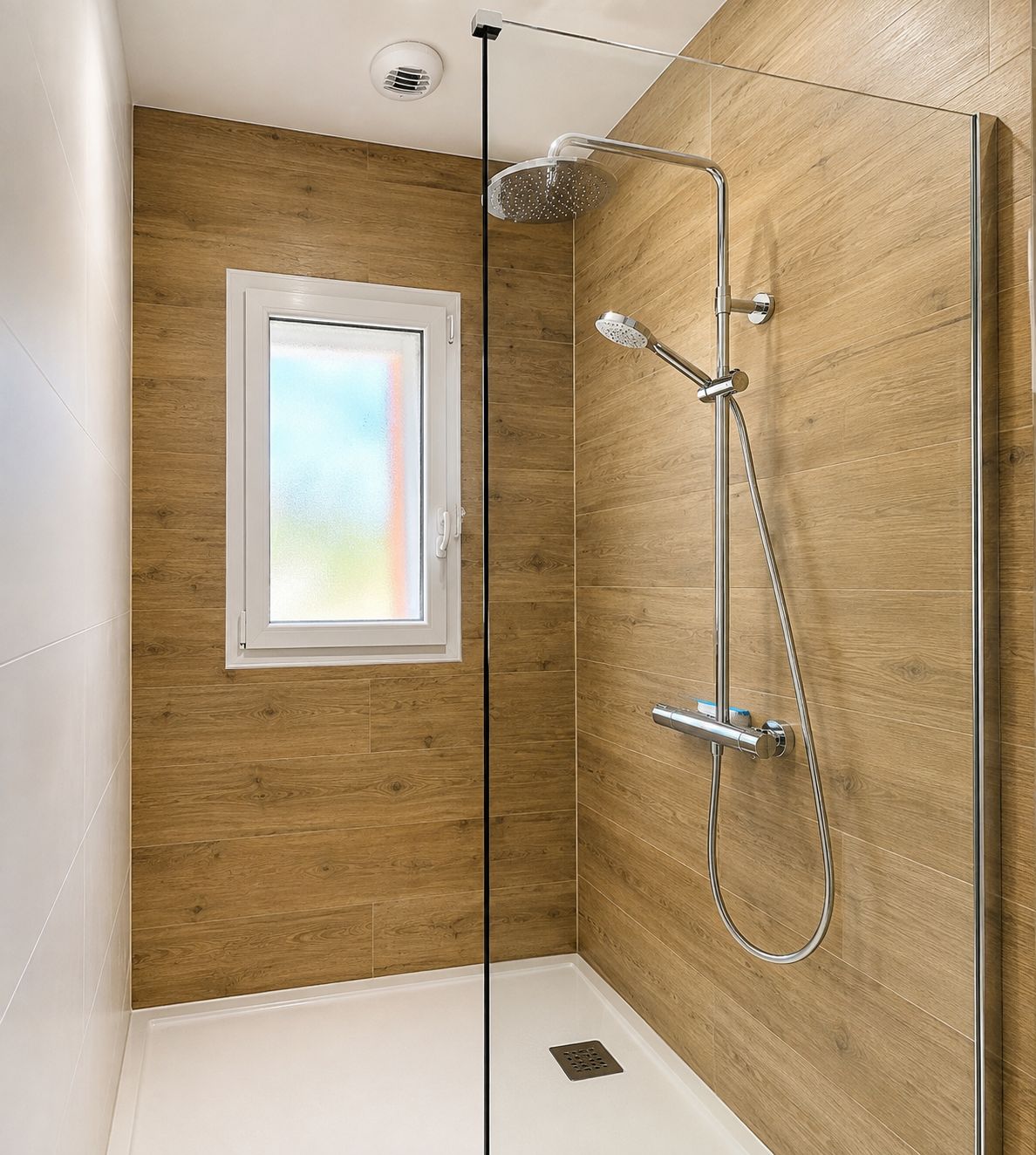 Une douche équipée d’un pommeau de douche à effet pluie, d’un pommeau de douche à main et d’un flexible de douche à main.