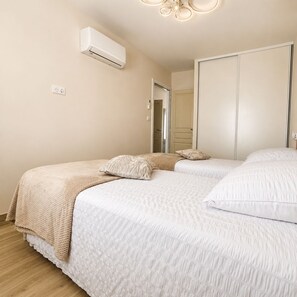 Ein Schlafzimmer mit zwei Betten, einem Kleiderschrank, einer Klimaanlage und einem Deckenventilator.