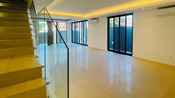 Un interior espacioso con una escalera que conduce a pisos superiores, ventanas amplias y un diseño moderno.