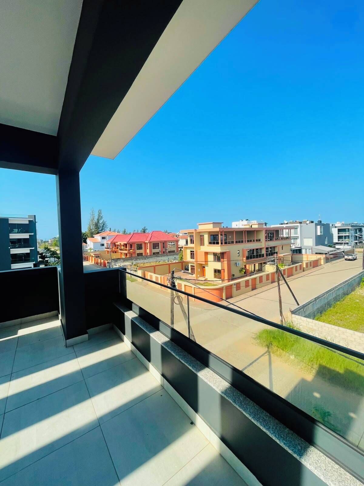 A balcony with a clear view of a residential area, featuring modern buildings and a spacious street.