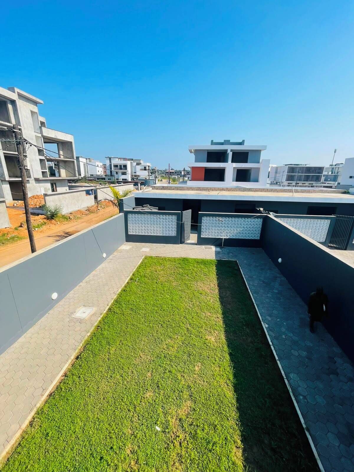 Eine Dachterrasse mit Rasenfläche, ein modernes Gebäude im Hintergrund und ein klarer Himmel.