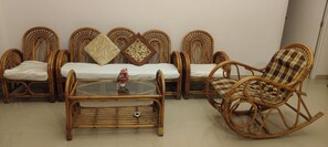 A room with wicker furniture, including a sofa set and a rocking chair, with a glass coffee table in the center. - Goa Colva beach apartment Reliance sea mist (Colva)