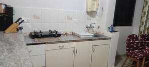 A kitchen with a gas stove, sink, and cabinets. - Goa Colva beach apartment Reliance sea mist (Colva)