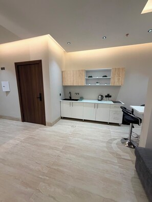 A modern kitchen with white cabinets, a black countertop, and a built-in sink. - Modern and cozy apartment in charming Madinah (Madinah)