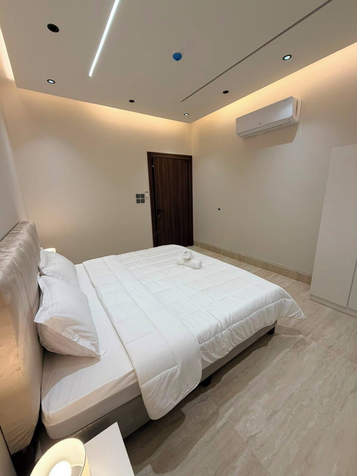 Une chambre à coucher moderne, équipée d’un lit, d’une table de chevet, d’un appareil de climatisation et d’une porte.