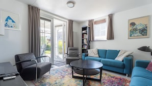A modern living room with a sofa, armchair, coffee table, and a bookshelf. - Vacation Home Wolphaarsdijk 9b (Wolphaartsdijk)