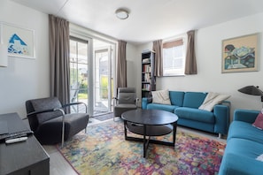 A modern living room with a sofa, armchair, coffee table, and a bookshelf. - Vacation Home Wolphaarsdijk 9b (Wolphaartsdijk)