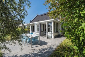 Una casa con un porche techado, piscina y jardín.