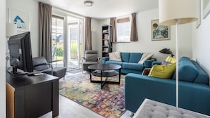 A modern living room with a sofa, armchair, coffee table, and a television. - Vacation Home Wolphaarsdijk 9b (Wolphaartsdijk)