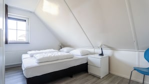 A bedroom with a bed, bedside table, chair, and a window. - Vacation Home Wolphaarsdijk 9b (Wolphaartsdijk)