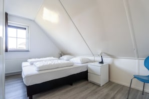 A bedroom with a bed, bedside table, chair, and a window. - Vacation Home Wolphaarsdijk 9b (Wolphaartsdijk)