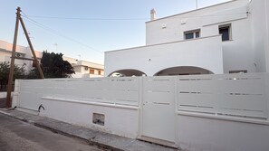 A white building with a gated entrance, a visible chimney, and a clear sky. - Corallo Apartment (Porto Cesareo)