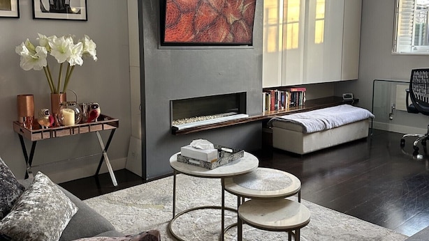 Een moderne woonkamer met een bank, een salontafel, een aan de muur bevestigde televisie en een boekenkast.