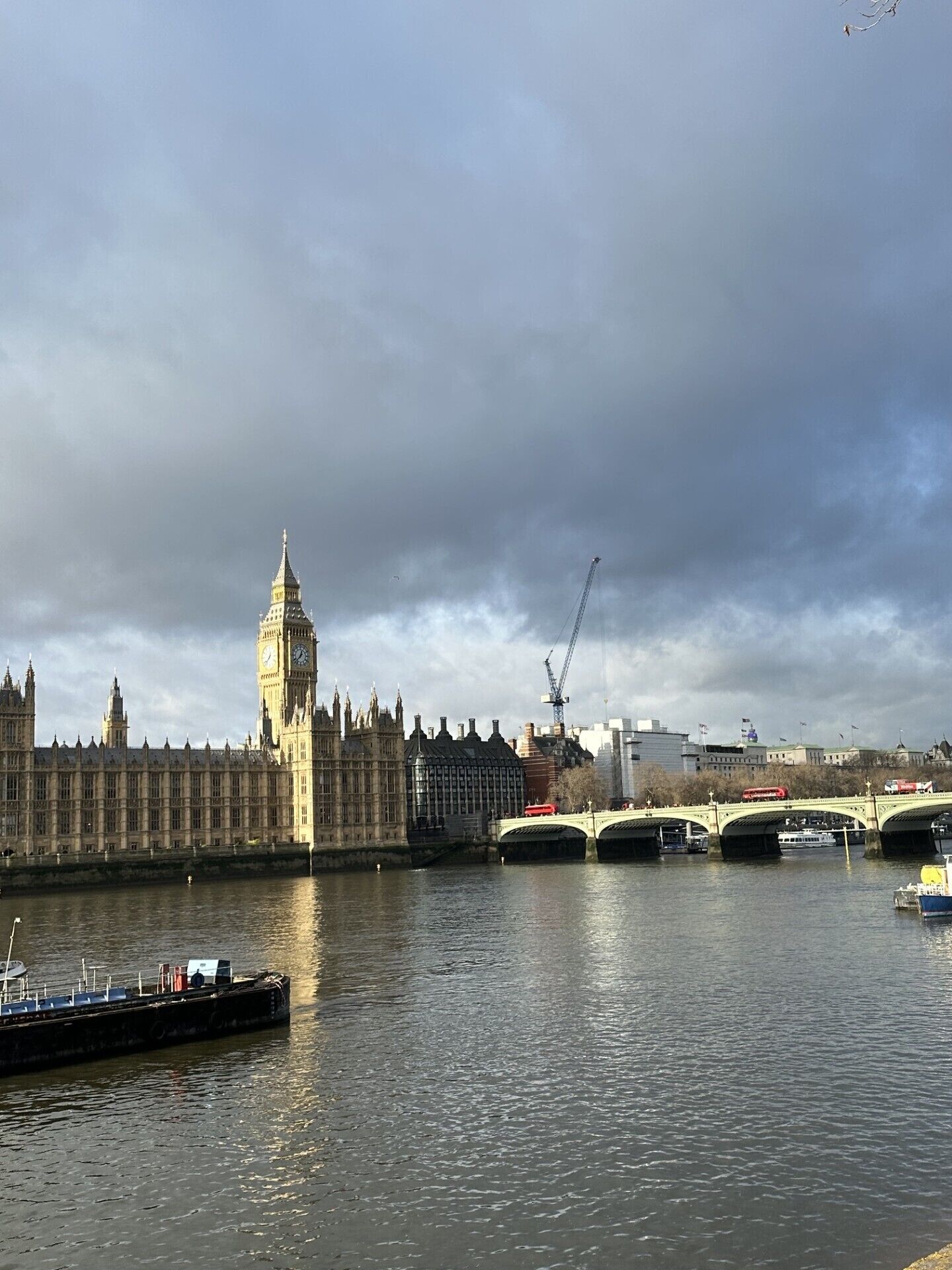 A river with a bridge and a historic building with a clock tower.