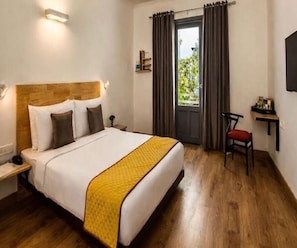 Een hotelkamer met een bed, een stoel, een bureau en een raam met gordijnen.