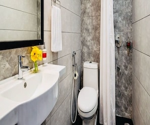Een badkamer met een wit wastafelmeubel, een toilet en een douchegedeelte.