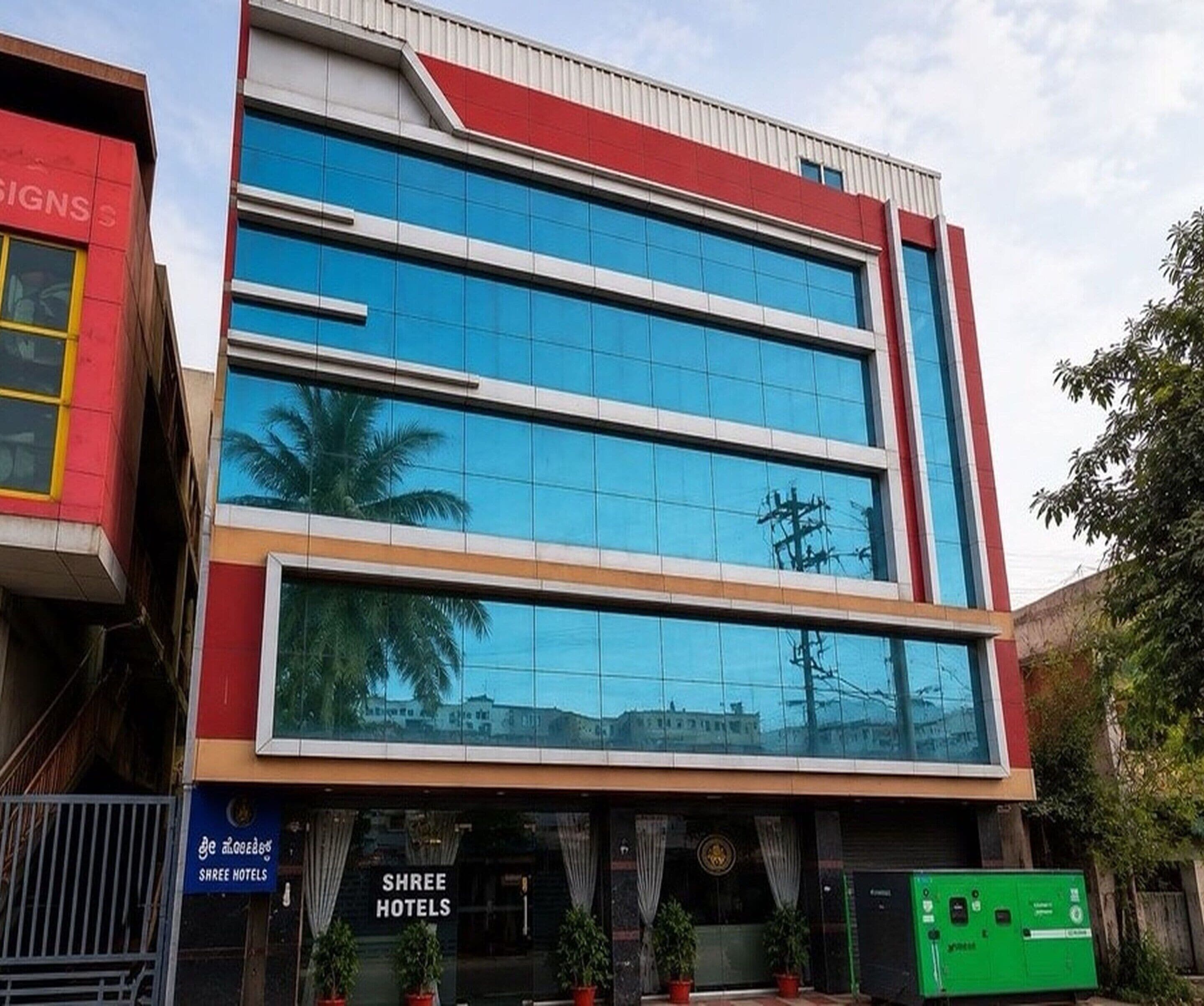 A modern hotel building with a glass facade, multiple floors, and a red and white exterior.