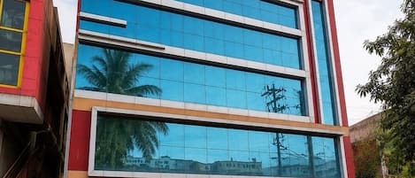A modern hotel building with a glass facade, multiple floors, and a red and white exterior.