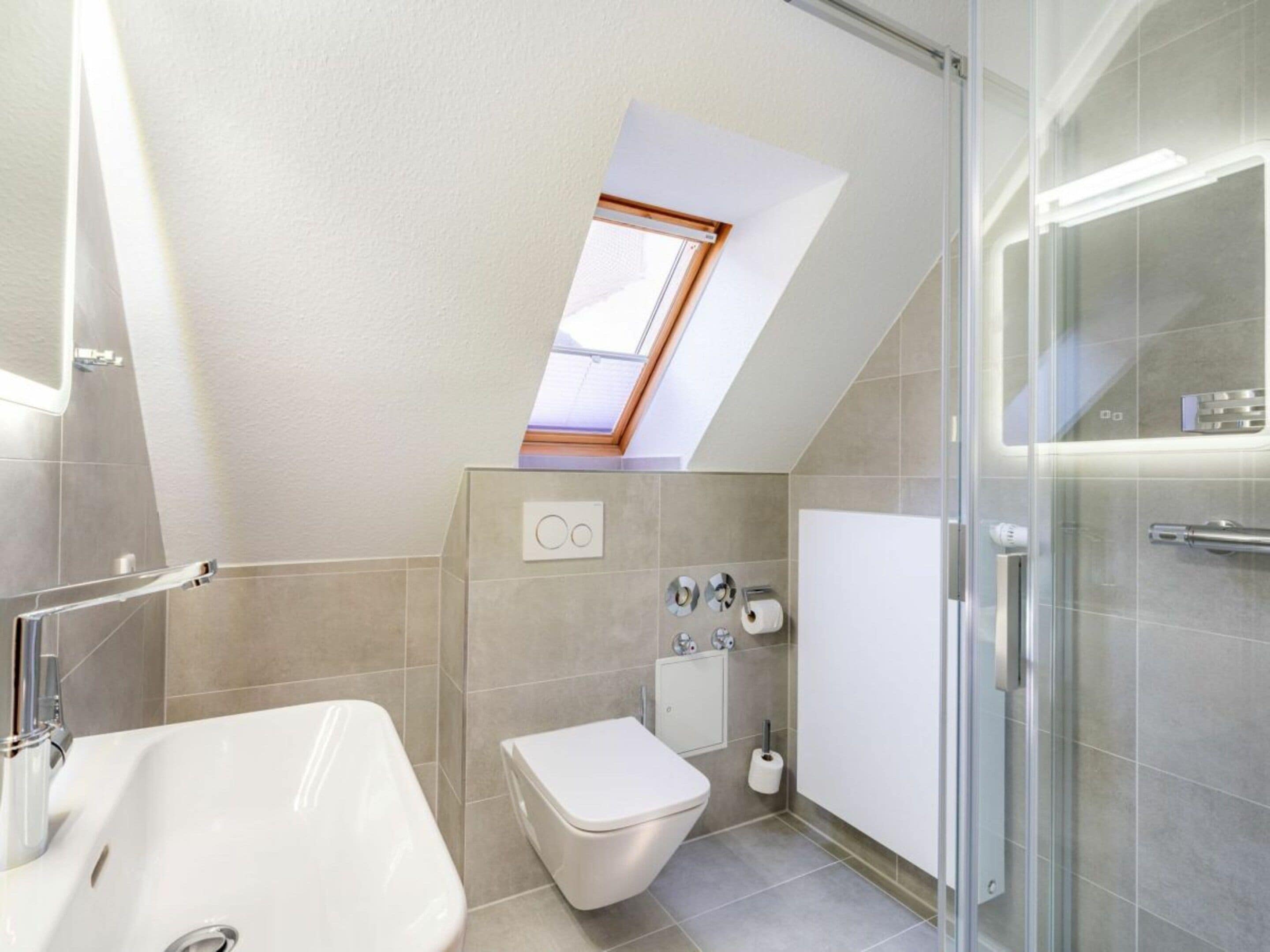 Et moderne badeværelse med ovenlys, bruser og toilet.