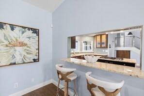 A modern kitchen with a marble countertop, two bar stools, and a large mirror reflecting the interior. - NEW! Luxury Waterfront Retreat, Private Pool, Dock & Sunrise Views 3Bed 3.5 Bath (St. Petersburg)