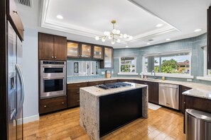 A modern kitchen with built-in appliances, a central island, and a view of the outdoors. - NEW! Luxury Waterfront Retreat, Private Pool, Dock & Sunrise Views 3Bed 3.5 Bath (St. Petersburg)