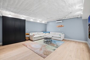Een woonkamer met een modulaire bank, een salontafel, een zwarte garderobe en een kamerbreed tapijt met een patroon.