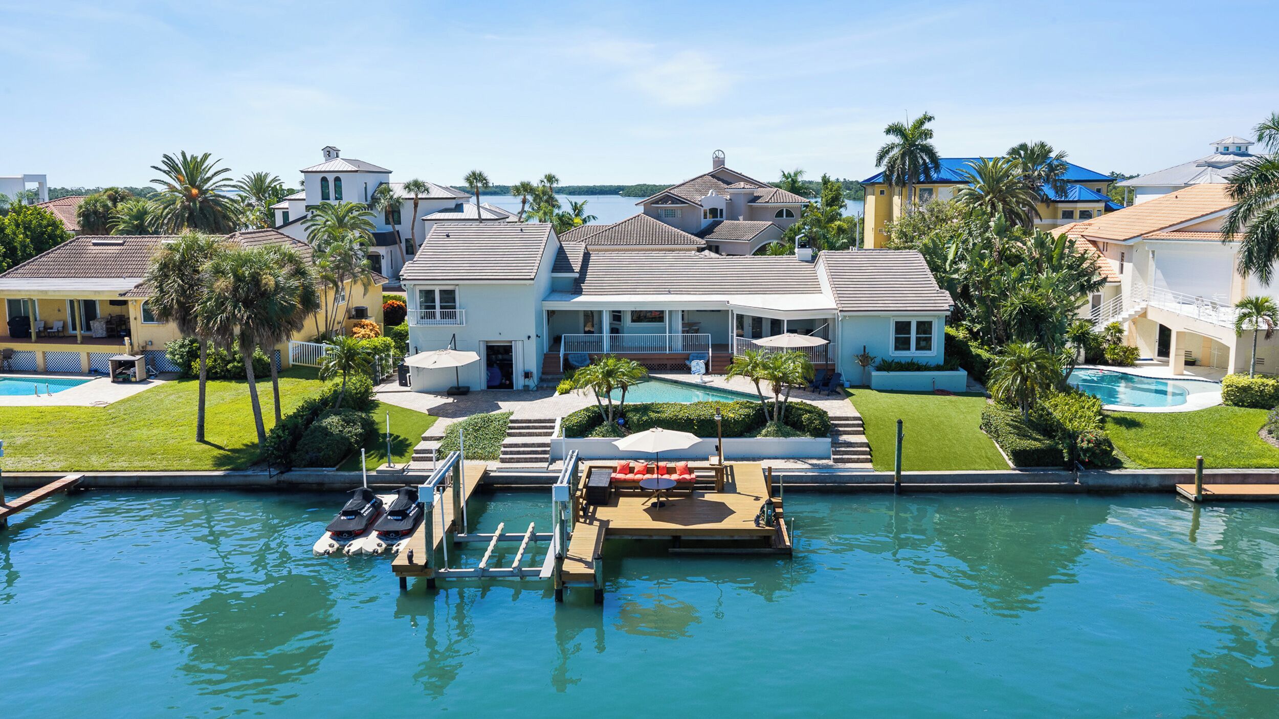 A residential property with a swimming pool, dock, and boats.