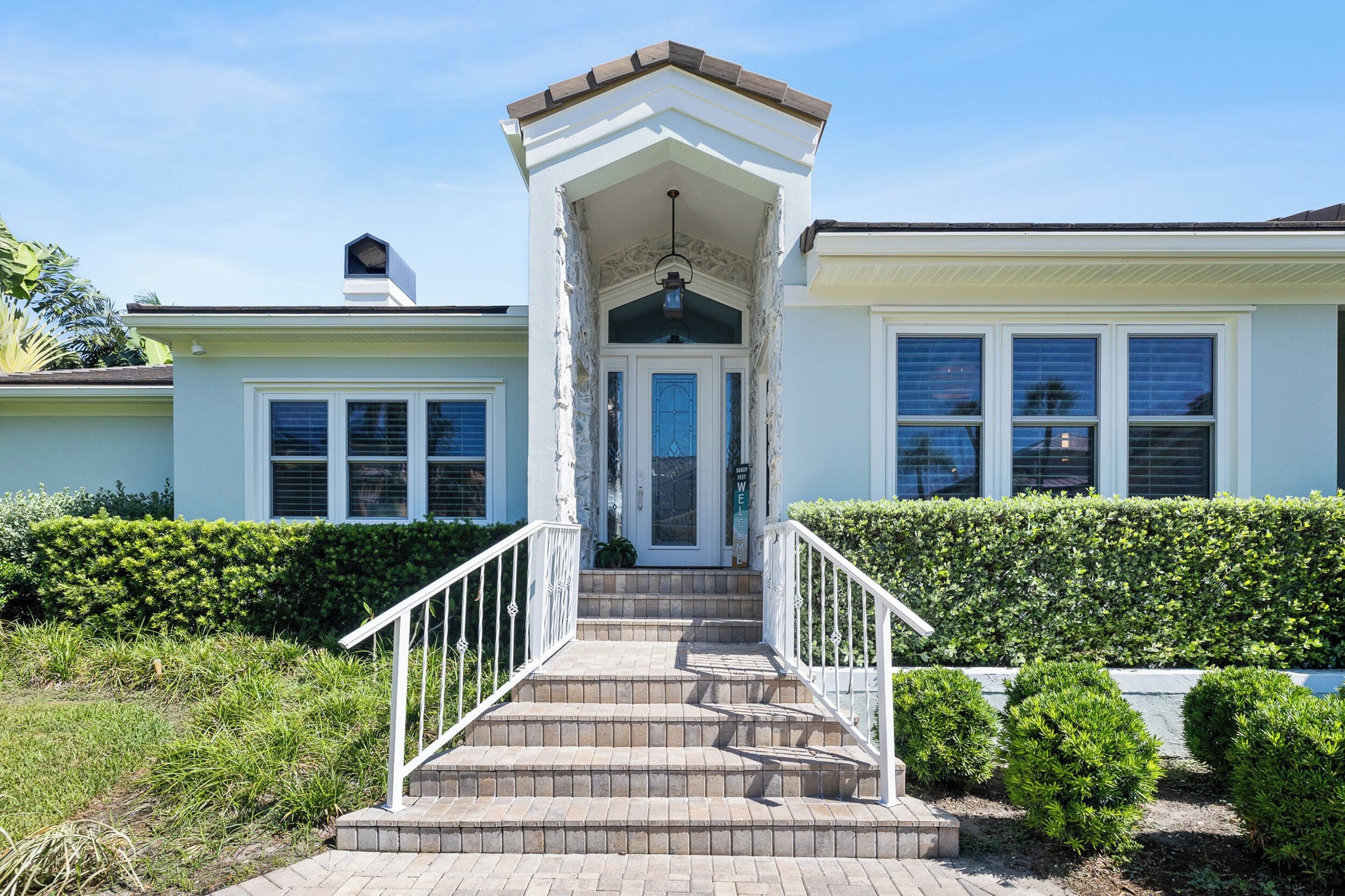 A two-story house with a central entrance, a covered porch, and a brick staircase leading to the front door.