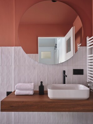 Une salle de bain avec un meuble-lavabo en bois, un lavabo blanc et un miroir.