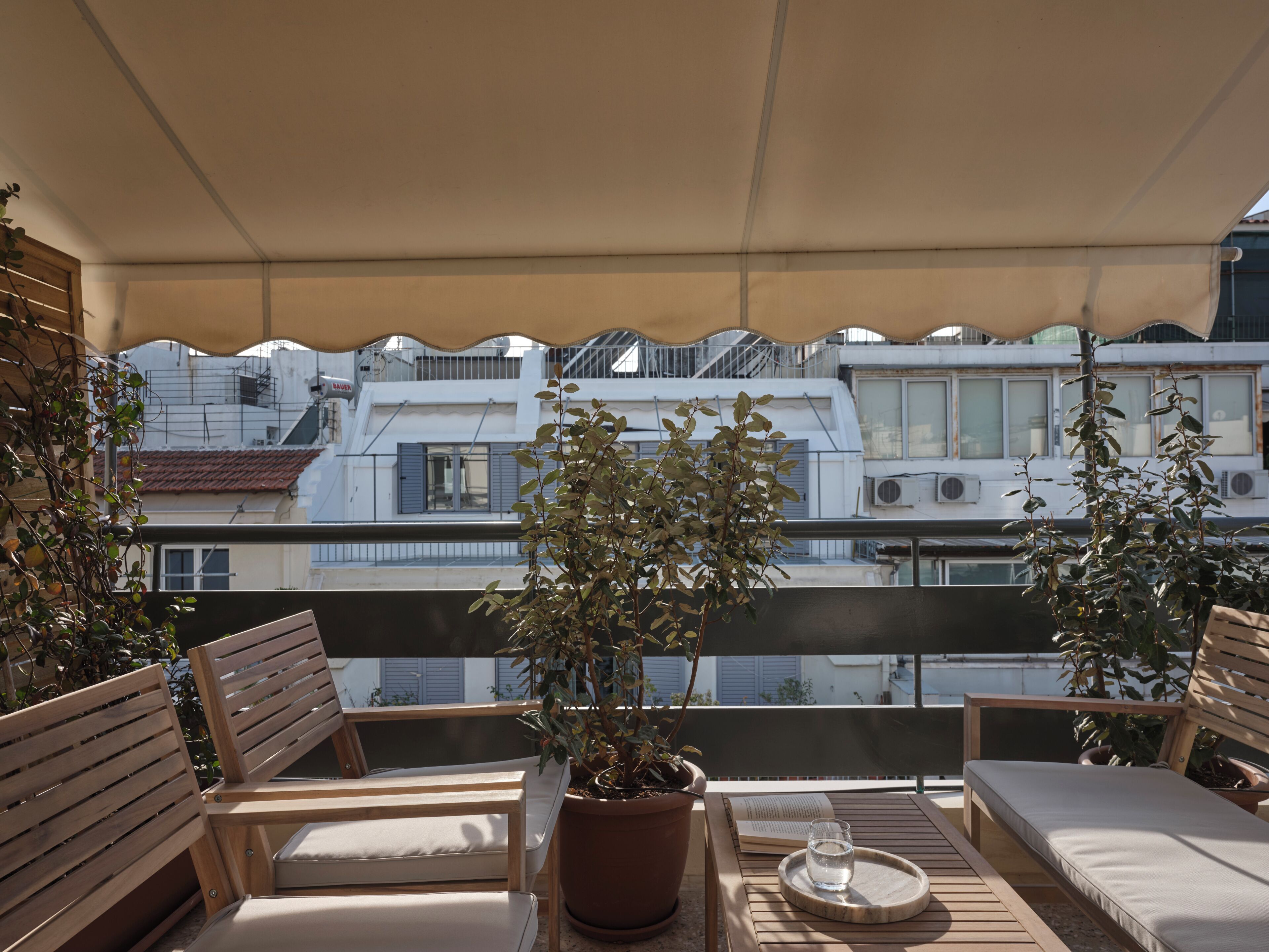 A balcony with wooden furniture, a potted plant, and a glass of water.
