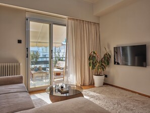 Un salon comprenant un canapé, une table basse, un téléviseur, une porte-fenêtre coulissante et une plante en pot.