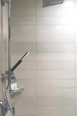 Ein Duschbereich mit Handbrause und Ablagefläche für Toilettenartikel.