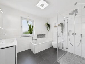 A modern bathroom with a bathtub, toilet, and shower area. - Gemütliches Ferienhaus im 3 Schlafzimmer 2 Bäder (Regen)
