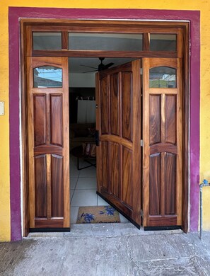 A wooden door with glass panels, leading to an interior space with a ceiling fan.
