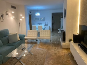 A modern living room with a sofa, a glass coffee table, and a TV on a stand. - The Golf View Marbella, a peaceful golf retreat in Guadalmina (San Pedro Alcántara)