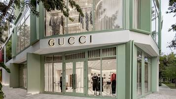 Ein GUCCI Geschäft mit einer modernen Fassade, großen Glasfenstern und dem deutlich sichtbaren Markennamen über dem Eingang.