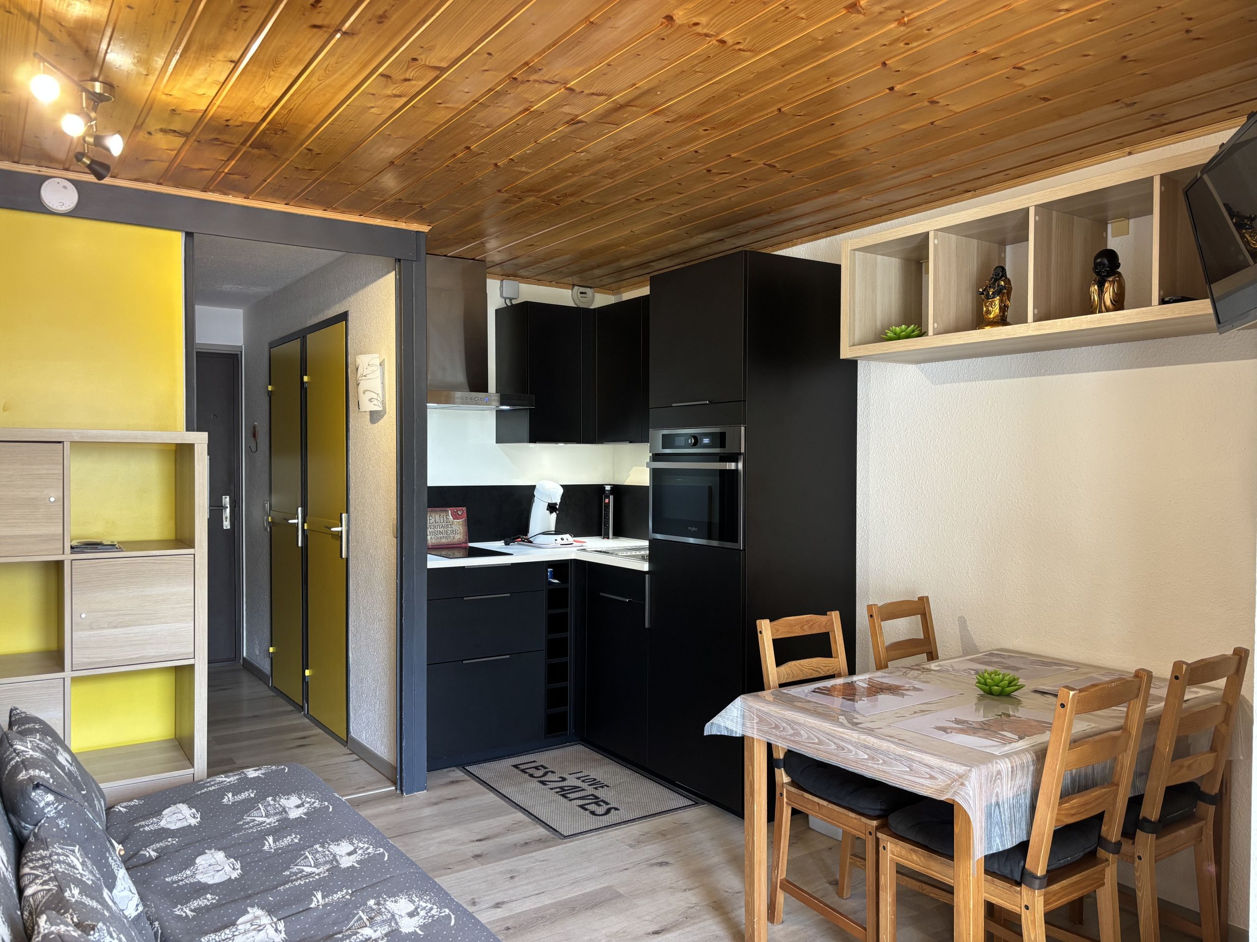 A compact kitchen with black cabinets, a microwave, and a stove. There is a dining area with a table and chairs.