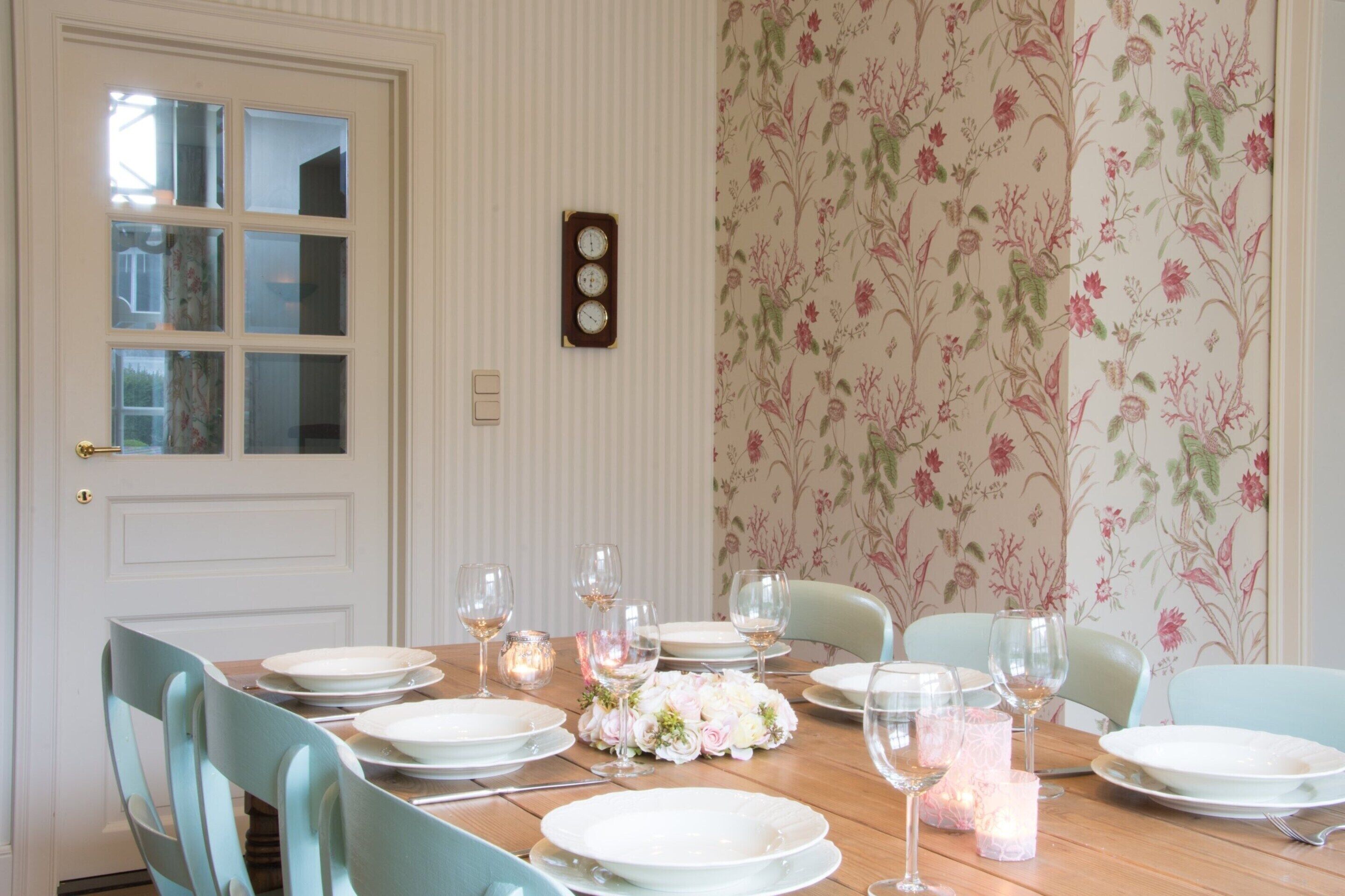 A dining room with a wooden table set for six, surrounded by light blue chairs.
